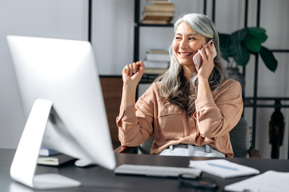 woman in front of computer while using her phone