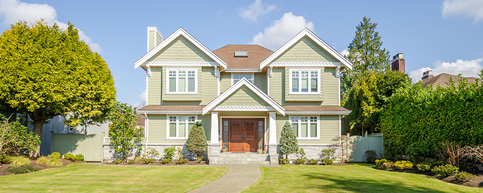 Two‑storey green suburban house with a central porch, manicured lawn and trees - https://www.fairwayinsuranceadvisors.com/